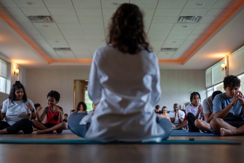 Brittany guiding a seated group meditation on yoga mats